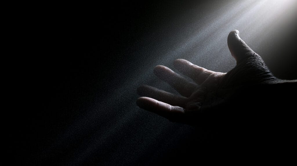 A single hand reaching into darkness, fingertips extended toward the unseen.
