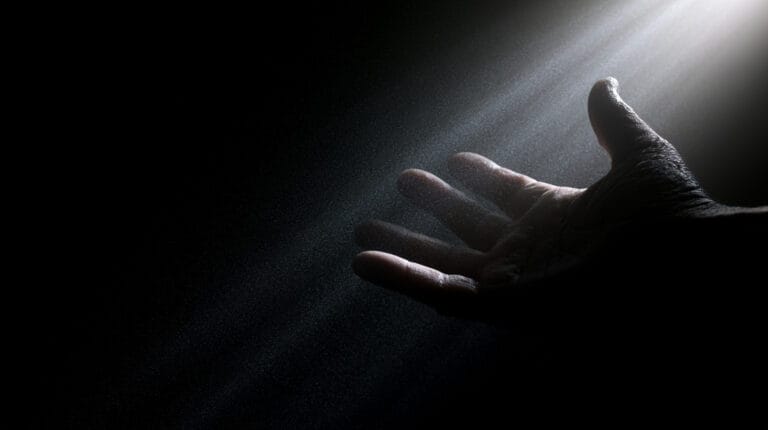 A single hand reaching into darkness, fingertips extended toward the unseen.